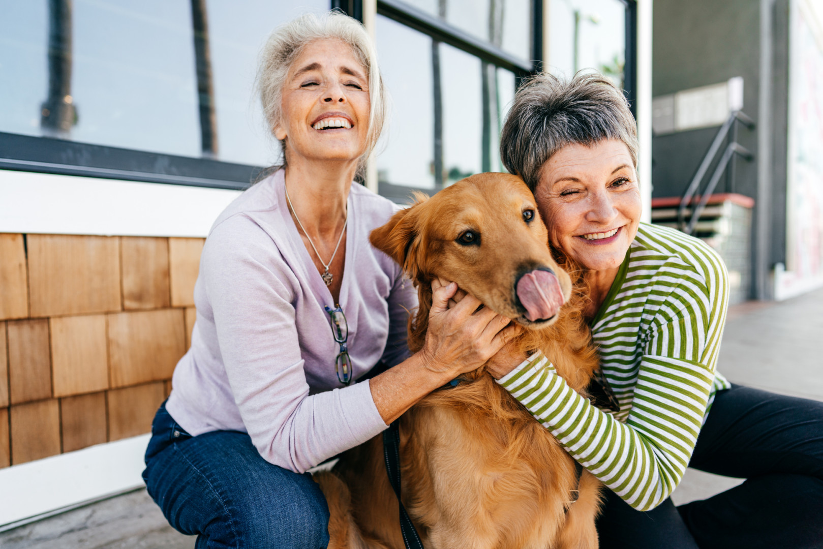 Older women smiling at the camera whilst hugging a golden retriever dog.